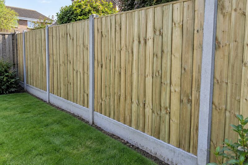 Illustrative close-up of closeboard fencing between slotted concrete posts above concrete gravel boards