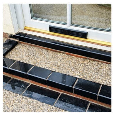 Close-up of resin bound steps finished with black edging up to a patio door
