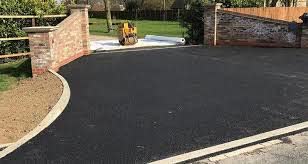 Newly laid tarmac driveway between brick pillars, finished down to a dropped kerb at the road